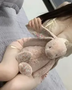 Bàn tay ôm gấu bông nhỏ trước váy hồng nhạt, tạo cảm giác đầy đặn dịu dàng