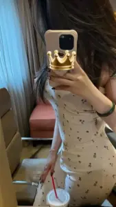 Cô gái chụp gương trong phòng, váy trắng họa tiết nhỏ ôm dáng, tóc dài che nửa mặt