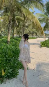 Bóng dáng váy trắng đi trên lối cát dưới hàng dừa mang vẻ dịu dàng đi biển