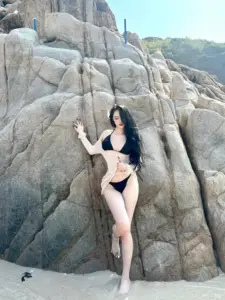 Giữa nền đá xám cô gái bikini đen tạo dáng ngồi gợi cảm với mái tóc dài