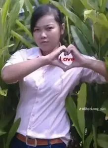 Cô gái mặc áo rộng đứng trước tường trắng, dáng pose cứng nhắc nhưng nhìn rất duyên