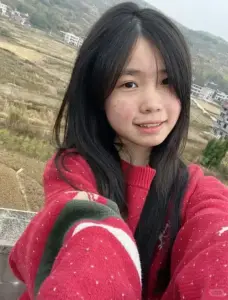 Cô gái áo đỏ selfie ngoài triền đất, tóc đen buông nhẹ và nụ cười ngại ngùng