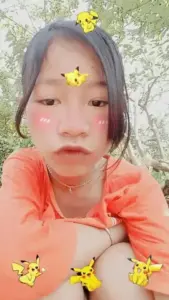 Gương mặt phủ filter má hồng, áo cam nổi bật với hoa vàng nhỏ nhìn khá tấu hài