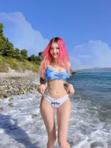 Sóng biển sau tôn dáng mỹ nhân tóc hồng mặc bikini xanh, tay chống eo tự tin