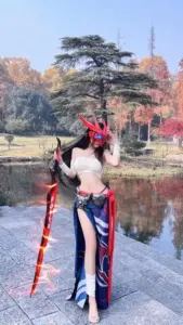 Nữ coser diện outfit Akali xanh đen, cầm kunai tạo dáng lạnh lùng dưới ánh đèn đường phố