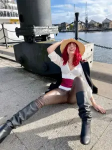 Cô nàng tóc cam cosplay Nami tạo dáng tự tin bên bản đồ biển và áo crop top xanh nổi bật