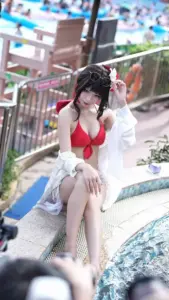 Thiếu nữ tóc đen ngồi bên hồ nước trong outfit đỏ trắng, biểu cảm gợi cảm nhẹ nhàng