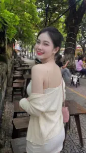 Nàng tóc đen ngoảnh cười ngoài trời áo trễ vai trắng tạo nét duyên gần gũi