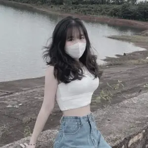 Bên bờ sông, cô gái đeo khẩu trang trắng mặc croptop và chân váy denim trẻ trung