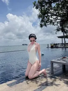 Hồ bơi vô cực, cô gái mặc đồ bơi trắng quỳ nhẹ, kính đen nổi bật