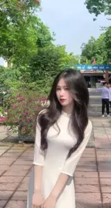 Trên lối đi lát gạch, cô gái tóc dài ngồi khép nép trong áo dài màu kem