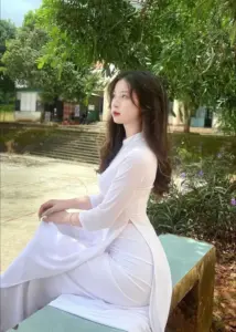 Bên ghế đá dưới tán cây, nàng mặc áo dài trắng nhìn xa với vẻ trầm dịu