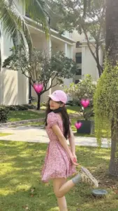 Giữa sân vườn nắng nhẹ, cô gái đội mũ hồng diện váy pinky đứng nghiêng dịu dàng