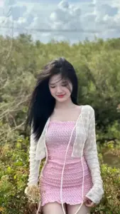 Ngoài đồng cỏ sáng, cô nàng khoác cardigan trắng trên váy hồng cười cúi đầu e ấp