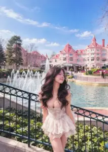 Bên đài phun nước, cô nàng xinh đẹp mặc váy hồng bồng, tóc xoăn bay tự nhiên
