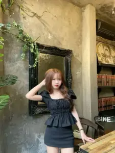 Trong góc quán cổ, cô gái váy đen ngồi vén tóc với vẻ mặt hơi e thẹn