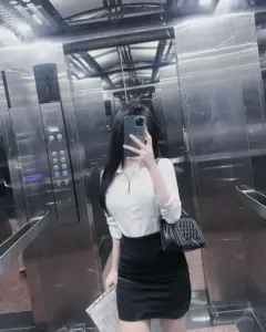 Cô gái mặc đầm ôm nhẹ cầm tập hồ sơ với dáng đứng thanh thoát nơi văn phòng