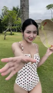 Nụ cười tươi trong đồ bơi chấm bi, bàn tay đưa gần ống kính đầy thân thiện