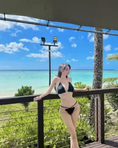 Dáng đứng tự tin trên ban công biển, bikini đen nổi bật trước trời xanh rực nắng