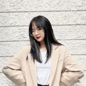 Cô gái trong phong cách Gấm Kami mặc blazer be đứng trước tường trắng với nụ cười nhẹ
