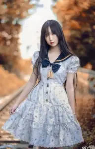 Giữa hàng cây vàng, nữ streamer diện váy thủy thủ xanh, đứng nhẹ với tóc dài đen
