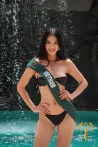 Khoảnh khắc người mẫu áo tắm bộ đen lệch vai cười tươi dưới thác nước nhân tạo