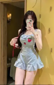 Góc studio nền trắng tôn rõ váy body xanh nhạt, cô gái mỉm cười cầm túi nhỏ