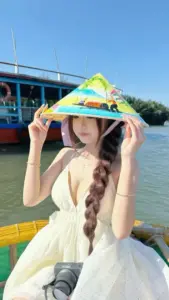 Trên boong tàu nàng thơ đội mũ màu rực rỡ mặc áo trắng cười dưới nắng hè