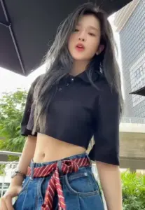 Ngoài ban công, cô gái mặc crop top đen, quần caro đỏ, tạo dáng tự tin