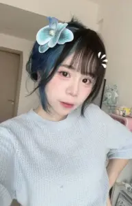 Cô nàng selfie trong áo xám, tóc đen kẹp nơ xanh, biểu cảm nhẹ nhàng trong phòng