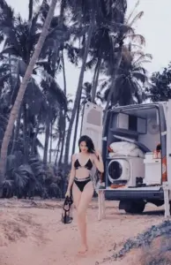 Bóng dáng nhỏ trên bãi cát mặc bikini đen, đứng yên giữa hàng dừa phủ nắng