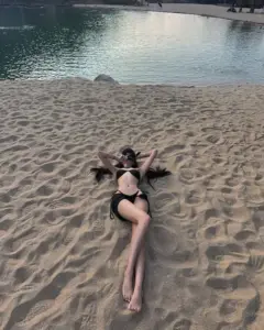 Trên bãi cát ẩm, cô mặc bikini đen nằm thư giãn với vẻ mỏng nhẹ tự nhiên