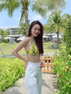 Nụ cười rạng rỡ nổi bật khi cô nàng mặc đồ tắm xanh phối quần trắng giữa khu vườn