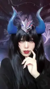 Nữ cosplayer đội mũ lưỡi trai, cầm điện thoại ngang tay như đang chờ vào trận cùng đồng đội