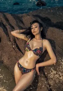 Góc chụp cao bắt Phương Oanh nằm thư thái trên bãi đá ướt với bikini hoa