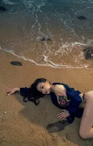 Khung hình bãi biển cho thấy cô diện bikini giữa bọt sóng, tóc đen xõa mềm