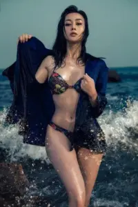 Con sóng vỗ sau lưng làm bikini hoa và áo choàng đen của cô thêm cuốn hút