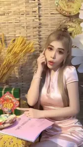 Bên bàn tiệc nhẹ, người đẹp tóc sáng mặc áo hồng ôm sát, chống cằm đầy duyên dáng