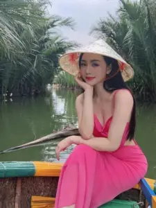 Chiếc nón lá che nắng, cô nàng mặc bikini hồng ngồi trên thuyền giữa rặng dừa