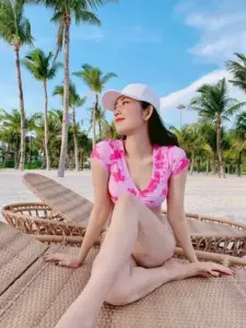 Dáng ngồi khép nép trên ghế biển làm cô gái áo tắm hồng toát vẻ mềm mại
