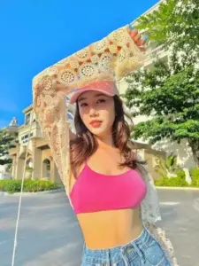 Nền trời xanh làm áo croptop hồng và mũ trắng của cô gái thêm nổi bật