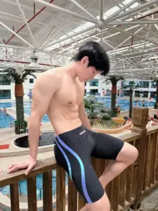 Bên hồ bơi trong nhà, nam thần cơ bụng mặc quần bơi đen xanh, nhìn xuống nhẹ nhàng