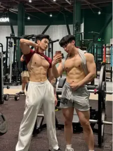 Hai người mẫu nam tạo dáng trong phòng gym, cơ bụng rõ nét, trang phục tập đơn giản