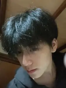 Ánh nhìn cậu bạn học trò tóc đen rủ che trán, áo tối màu và khung nền gỗ ấm