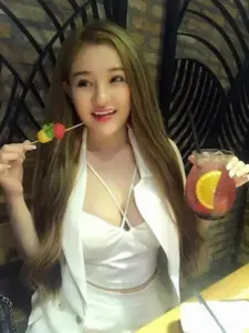 Trong góc chụp trong nhà, người đẹp cười nhẹ với váy trắng ôm dáng và ly nước nhỏ