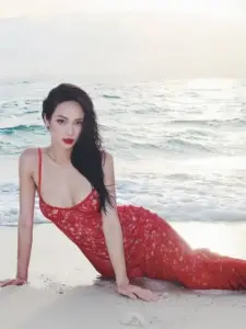 Sóng biển vỗ quanh người đẹp mặc váy đỏ ren, tạo dáng quỳ gối đầy mềm mại