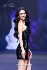 Từ góc chụp sân khấu, cô quay vai nhẹ trong đầm đen lấp lánh, môi cười rõ