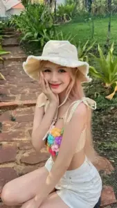 Dáng ngồi bên vườn của cô gái tóc sáng trong áo hai dây trắng tạo cảm giác nàng thơ dịu dàng