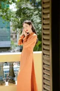 Thiếu nữ áo dài cam đứng tựa lan can gỗ, vẻ đẹp truyền thống hòa với nắng chiều