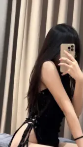 Phía rèm màu kem, cô nàng duyên dáng mặc váy đen selfie nghiêng bên gương